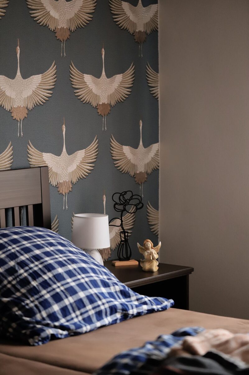 Bedroom accent wall finished with teal crane-motif wallpaper