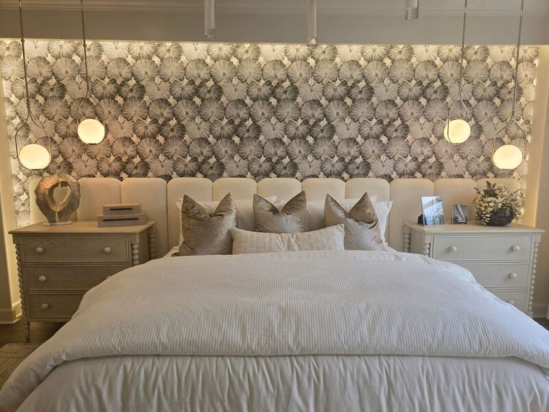 Bedroom with soft pewter textured wallpaper, an upholstered bed and warm pendant lighting