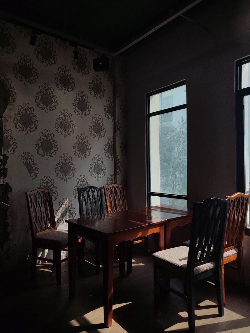 Dining room with a classic damask patterned wall, wood furniture and natural window light