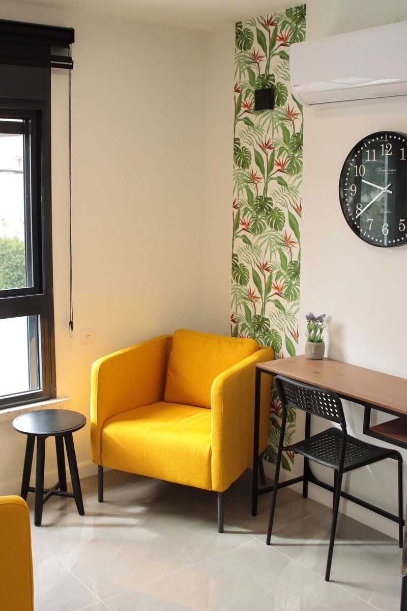 Home office with a green botanical accent wall, a desk and a warm armchair