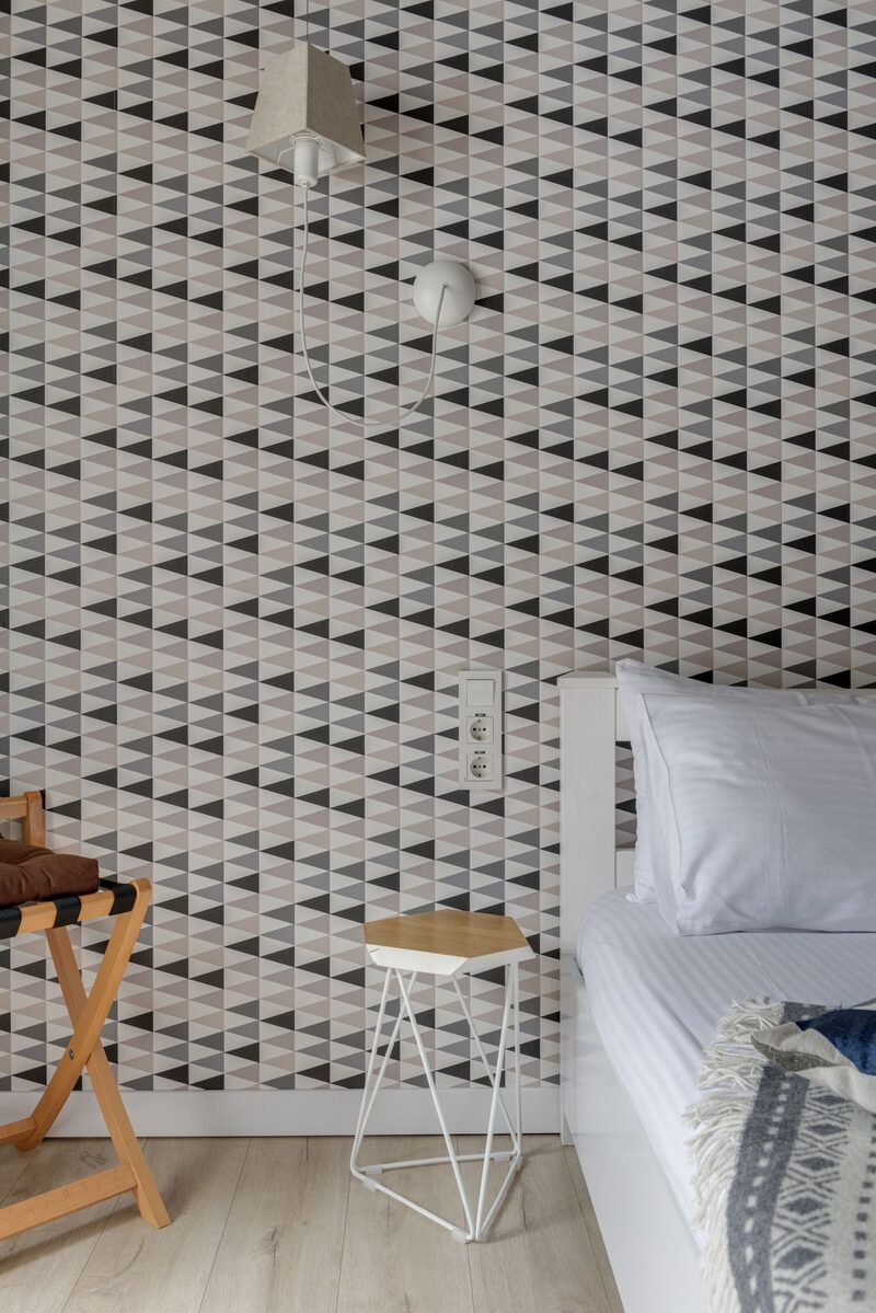 Bright transitional room with a black-and-white geometric wallpaper and a wooden stool